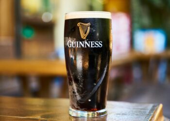 Close-up of a pint of Guinness stout beer on a wooden table in an indoor setting.