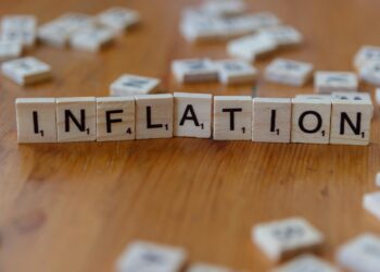 Scrabble letter tiles spelling 'INFLATION' on a wooden table, signifying economic concepts.