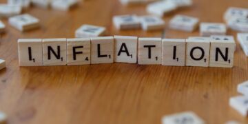Scrabble letter tiles spelling 'INFLATION' on a wooden table, signifying economic concepts.