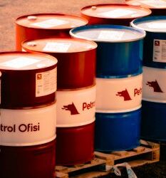 A collection of red and blue oil barrels labeled 'Petrol Ofisi' in an outdoor industrial setting in Turkey.