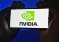 Hands holding a smartphone showing the NVIDIA logo on a bright screen.