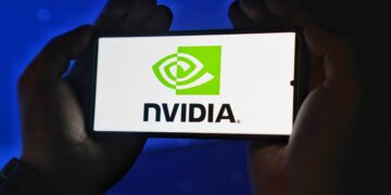 Hands holding a smartphone showing the NVIDIA logo on a bright screen.